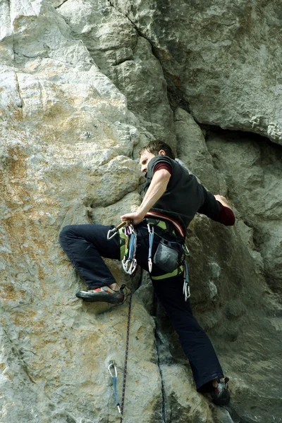 Young man climbing vertical wall with valley view on the background — Stock Photo, Image