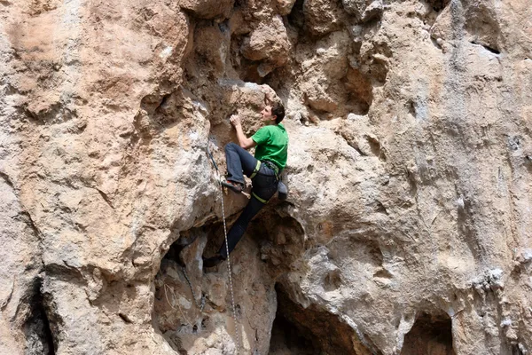 Young man climbing vertical wall with valley view on the background — Stock Photo, Image