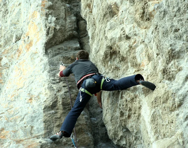 Jonge man klimmen verticale wand met valleizicht op de achtergrond — Stockfoto
