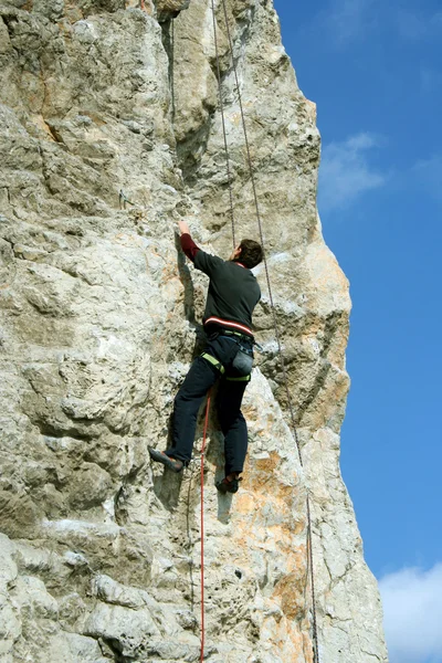 Jovem escalando parede vertical com vista para o vale no fundo — Fotografia de Stock