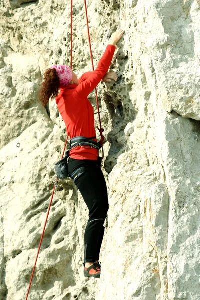 Jovem mulher escalando parede vertical com vista para o vale no fundo — Fotografia de Stock