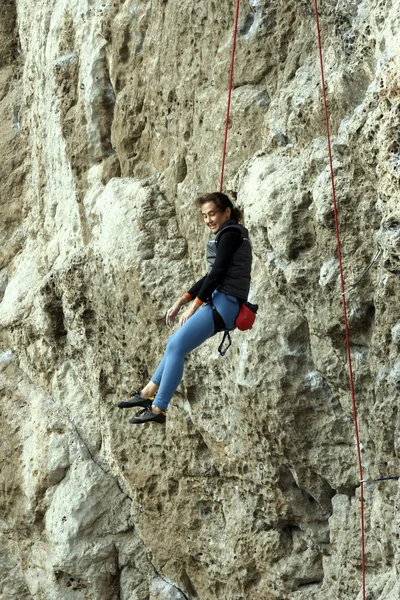 Young woman climbing vertical wall with valley view on the background — Stock Photo, Image