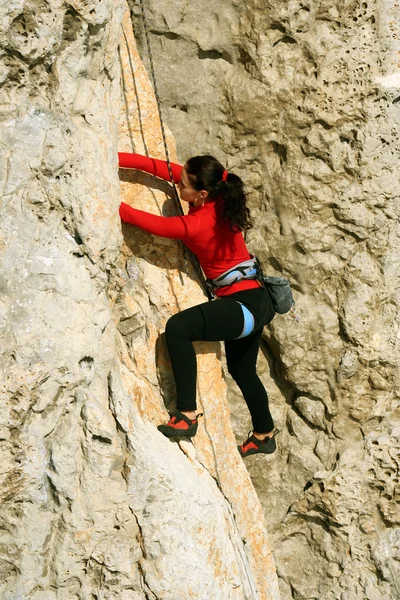 Νεαρή γυναίκα αναρρίχηση σε έναν τοίχο ασβεστόλιθος με ευρεία κοιλάδα στο παρασκήνιο — Φωτογραφία Αρχείου