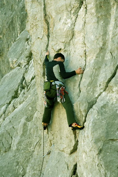 Joven escalando en una pared de piedra caliza con amplio valle en el fondo —  Fotos de Stock