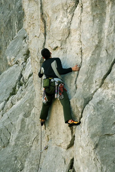 Młody człowiek wspinający się na wapienną ścianę z szeroką doliną na tle — Zdjęcie stockowe