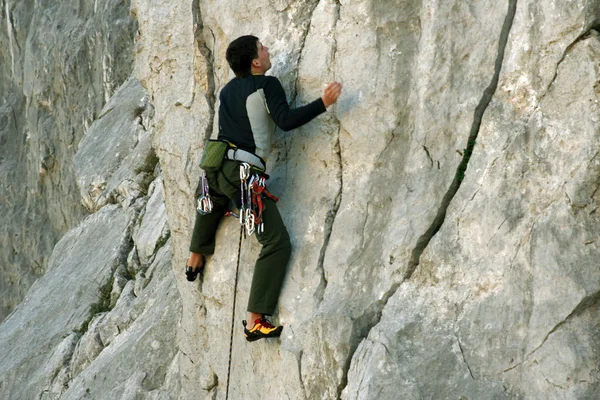 Jovem escalando em uma parede de pedra calcária com amplo vale no fundo — Fotografia de Stock