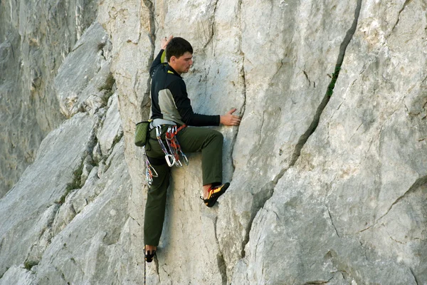 Joven escalando en una pared de piedra caliza con amplio valle en el fondo —  Fotos de Stock