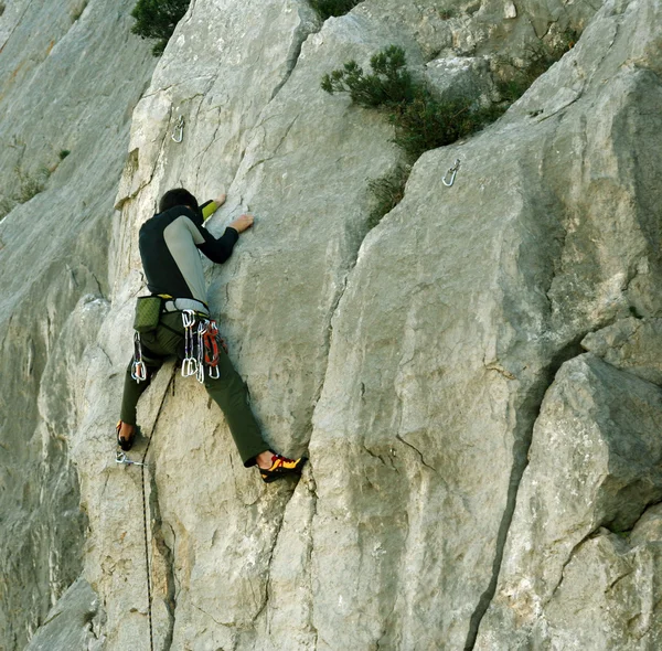 Jovem escalando em uma parede de pedra calcária com amplo vale no fundo — Fotografia de Stock