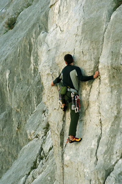 Joven escalando en una pared de piedra caliza con amplio valle en el fondo — Foto de Stock