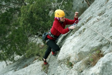 arka planda geniş vadi ile kireçtaşı duvara tırmanırken genç bir kadın