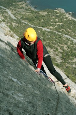 arka planda geniş vadi ile kireçtaşı duvara tırmanırken genç bir kadın