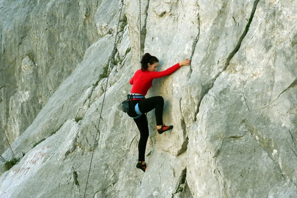 Junge Frau klettert an einer Kalksteinwand mit breitem Tal im Hintergrund — Stockfoto