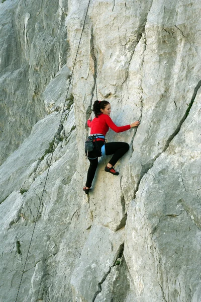 Jeune femme grimpant sur un mur de calcaire avec une large vallée sur le fond — Photo