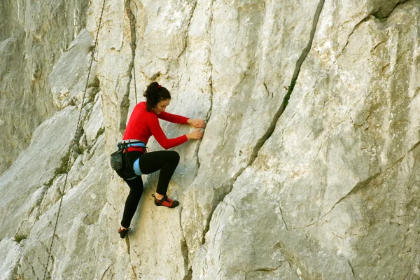 Junge Frau klettert an einer Kalksteinwand mit breitem Tal im Hintergrund — Stockfoto