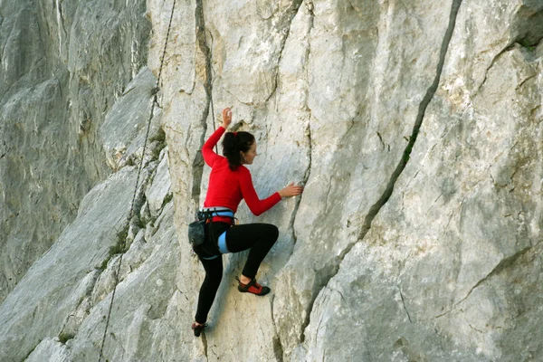 Junge Frau klettert an einer Kalksteinwand mit breitem Tal im Hintergrund — Stockfoto