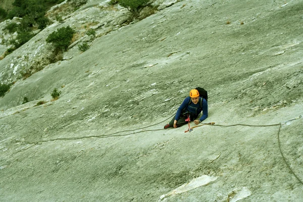 Jovem escalando em uma parede de pedra calcária com amplo vale no fundo — Fotografia de Stock