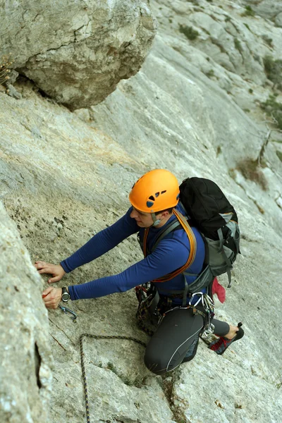 Giovane arrampicata su una parete calcarea con ampia valle sullo sfondo — Foto Stock