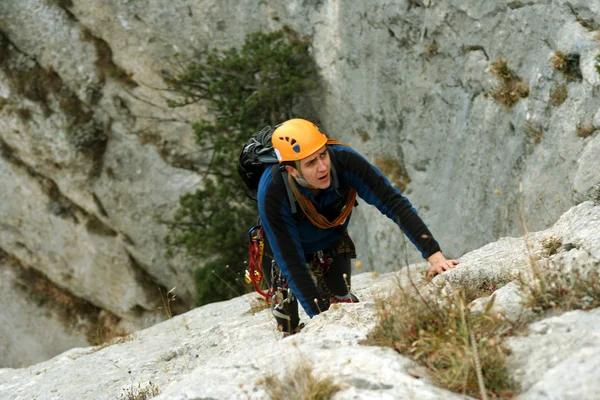Jongeman klimmend op een kalkstenen muur met brede vallei op de achtergrond — Stockfoto
