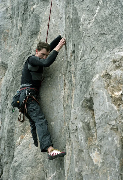 Young man climbing on a limestone wall with wide valley on the background — Stock Photo, Image