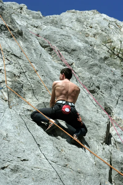 Jovem escalando em uma parede de pedra calcária com amplo vale no fundo — Fotografia de Stock