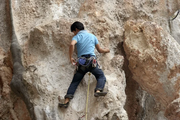 Joven escalando en una pared de piedra caliza con amplio valle en el fondo —  Fotos de Stock