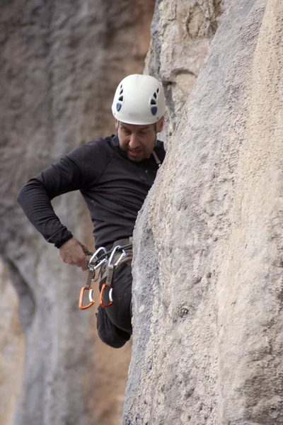 Jeune homme grimpant sur un mur de calcaire avec une large vallée sur le fond — Photo