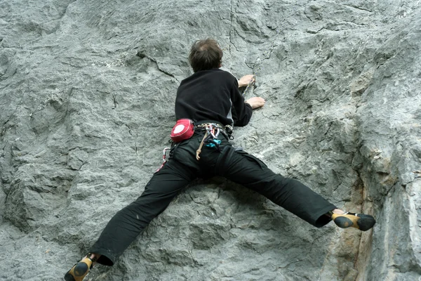 Joven escalando en una pared de piedra caliza con amplio valle en el fondo —  Fotos de Stock