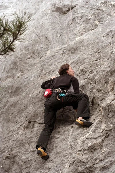 Jovem escalando em uma parede de pedra calcária com amplo vale no fundo — Fotografia de Stock