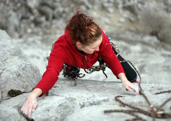 Νεαρή γυναίκα αναρρίχηση σε έναν τοίχο ασβεστόλιθος με ευρεία κοιλάδα — Φωτογραφία Αρχείου