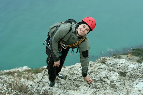 Joven escalando en una pared de piedra caliza con amplio valle en el fondo — Foto de Stock