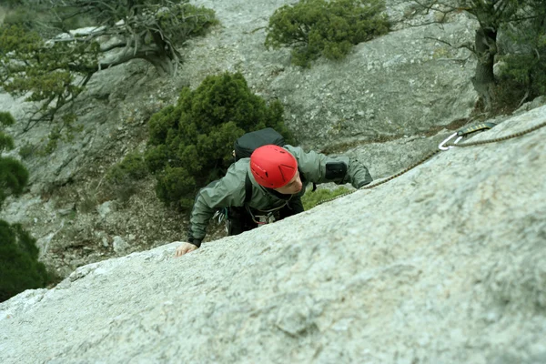 Joven escalando en una pared de piedra caliza con amplio valle en el fondo —  Fotos de Stock