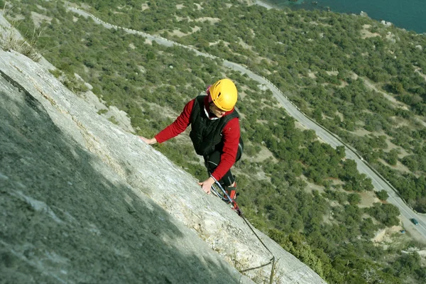 Giovane donna arrampicata su una parete calcarea con ampia valle sullo sfondo — Foto Stock