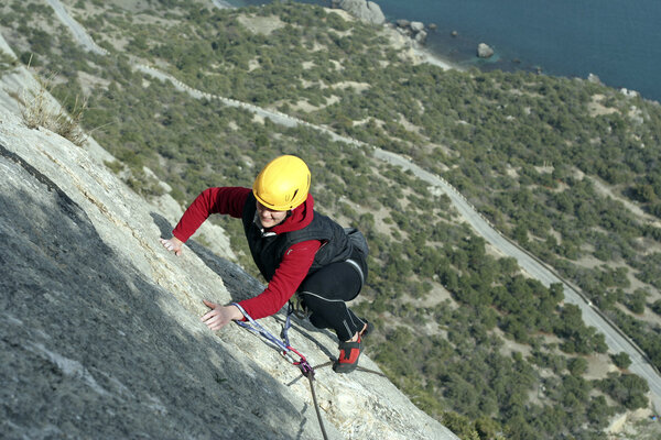 Young woman climbing on a limestone wall with wide valley on the background