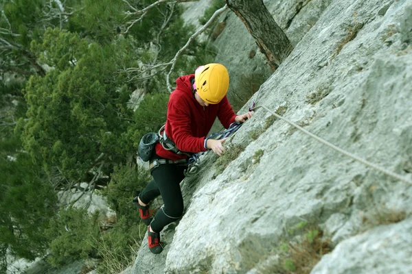 Giovane donna arrampicata su una parete calcarea con ampia valle sullo sfondo — Foto Stock