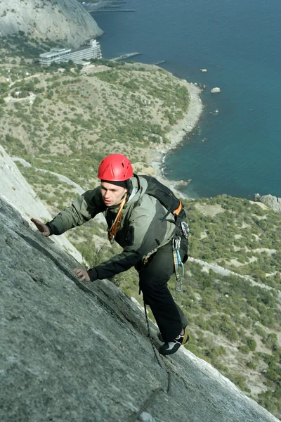 Joven escalando en una pared de piedra caliza con amplio valle en el fondo — Foto de Stock