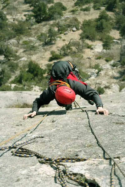 Junger Mann klettert an einer Kalksteinwand mit breitem Tal im Hintergrund — Stockfoto