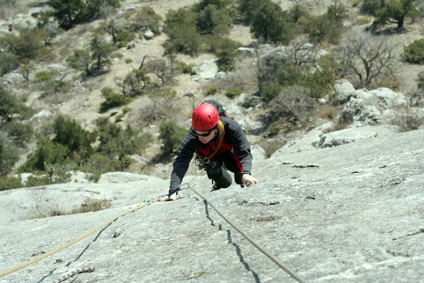 背景に広い谷を持つ石灰岩の壁に登る若い男 — ストック写真