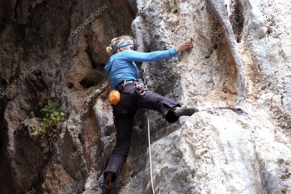 Young man climbing on a limestone wall with wide valley on the background