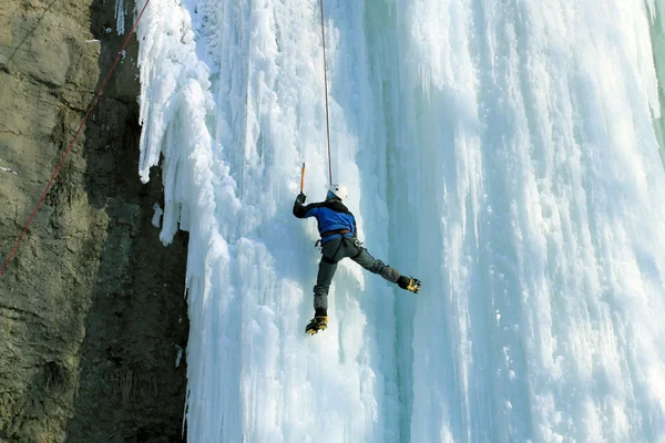 Man climbing frozen waterfall — Stock Photo, Image