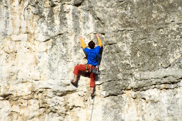 年轻人爬上石灰岩墙，后面是宽阔的山谷 — 图库照片