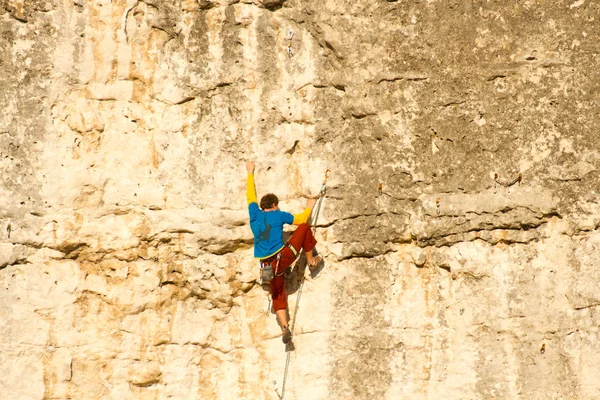 Młody człowiek pionowa ściana wspinaczkowa z widokiem na dolinę na tle — Zdjęcie stockowe