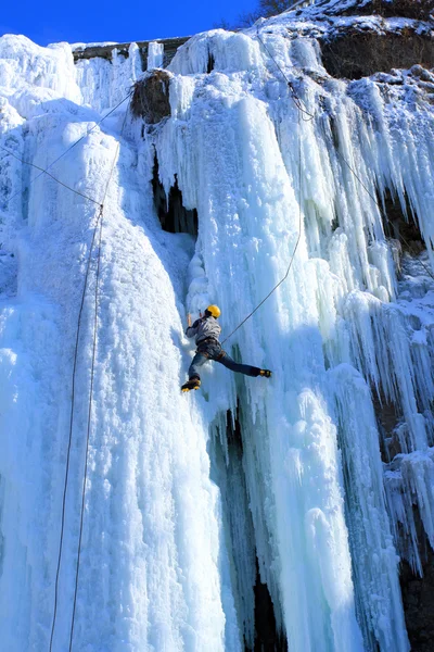 Man climbing frozen waterfall — Stock Photo, Image