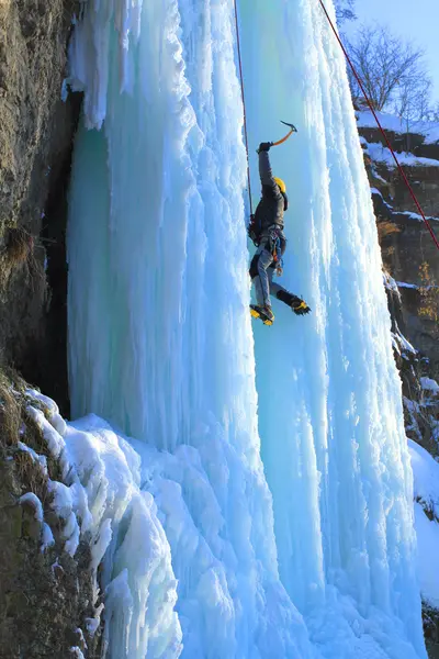 Man climbing frozen waterfall — Stock Photo, Image