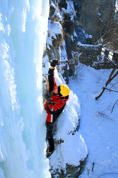 Man klättring frusna vattenfall — Stockfoto