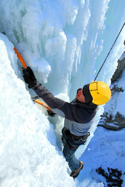 Man climbing frozen waterfall Stock Image