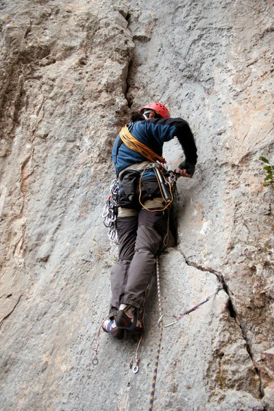 Mladý muž, lezení na svislé stěně s výhledem do údolí na pozadí — Stock fotografie