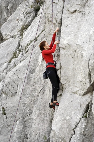 Jovem escalando parede vertical com vista para o vale no fundo — Fotografia de Stock