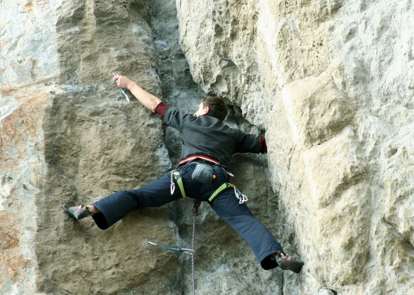 Young man climbing vertical wall with valley view on the background — Stock Photo, Image