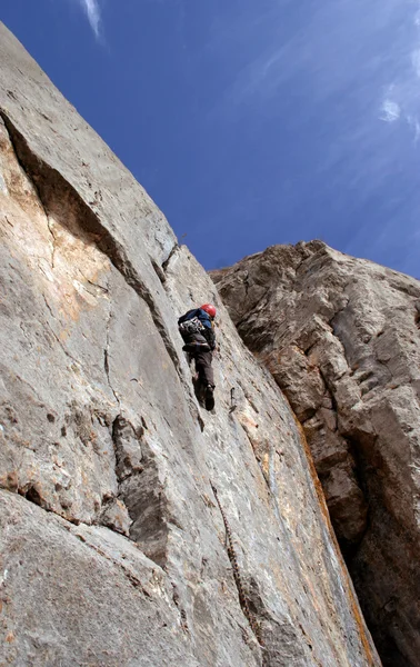 Hombre joven escalando pared vertical con vista al valle en el fondo —  Fotos de Stock