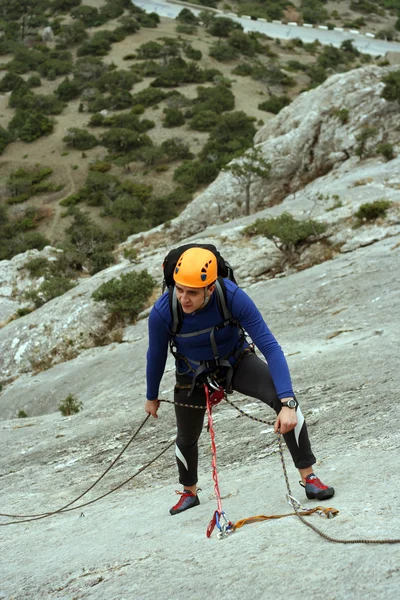 Jeune homme escalade mur vertical avec vue sur la vallée sur le fond — Photo